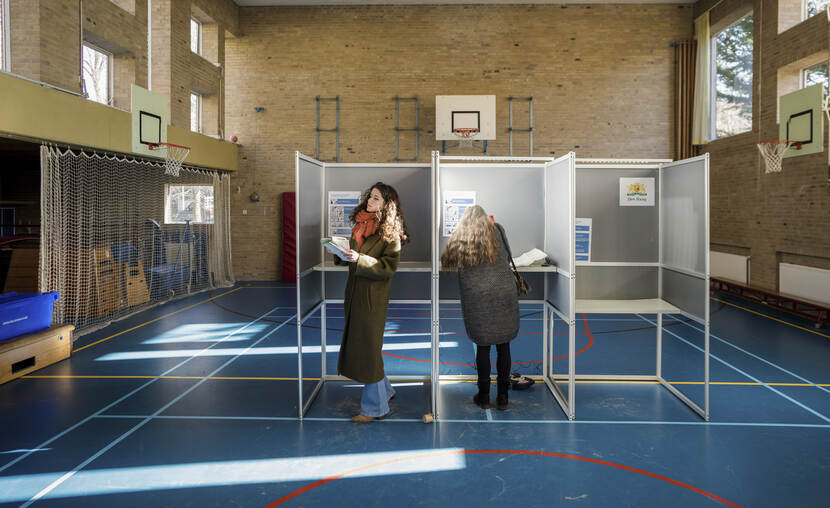 Twee vrouwen stemmen in een stemhokje